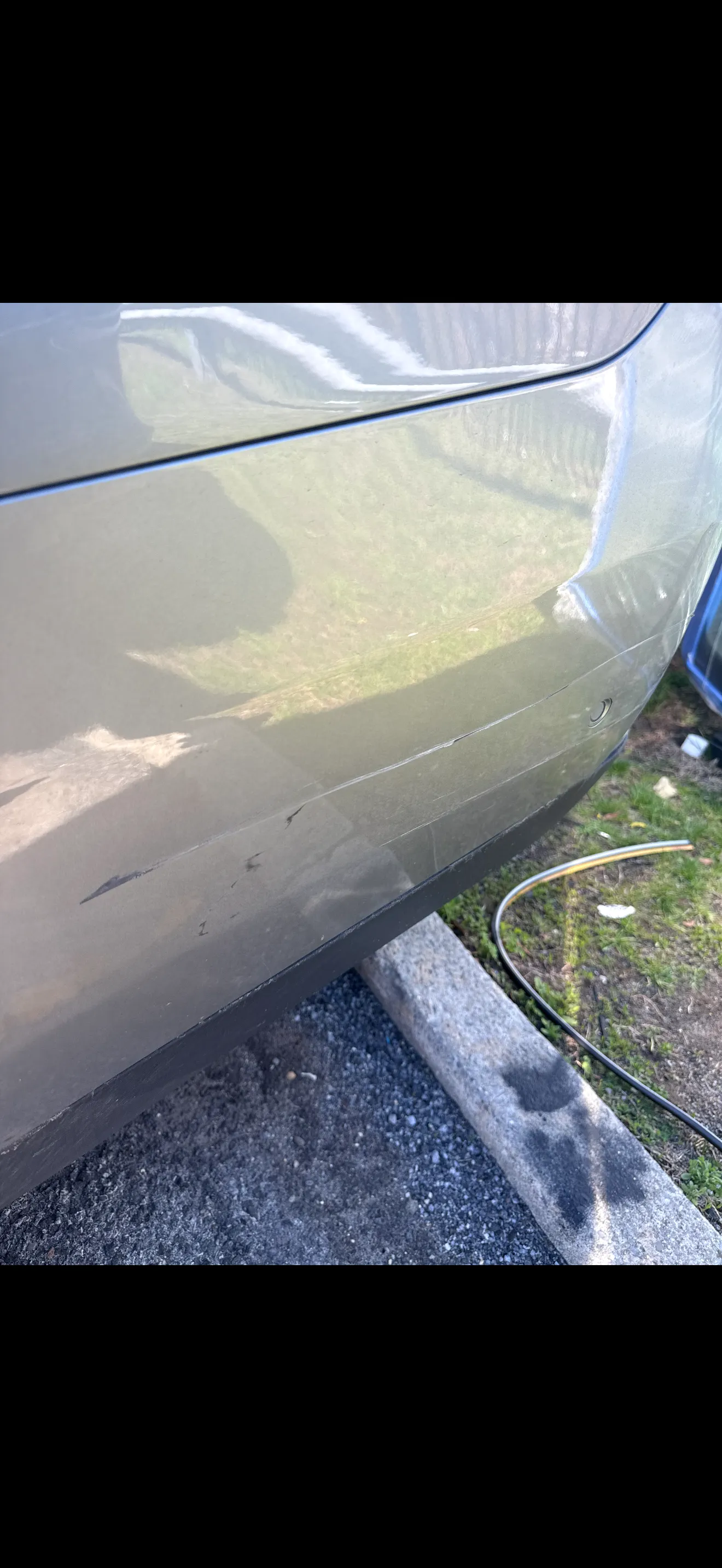 Gray Chevrolet Suburban rear quarter panel with a horizontal scrape across the lower body, before repair.